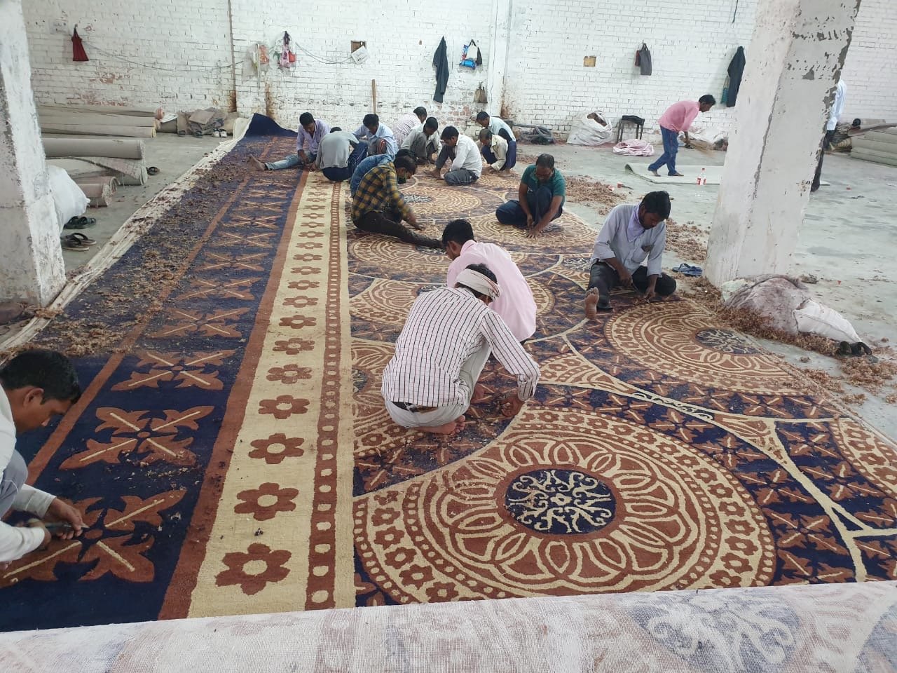 Artisans hand-tufting floral carpet design in Ahmedabad – large custom rug manufacturing for banquet halls and mosques.
